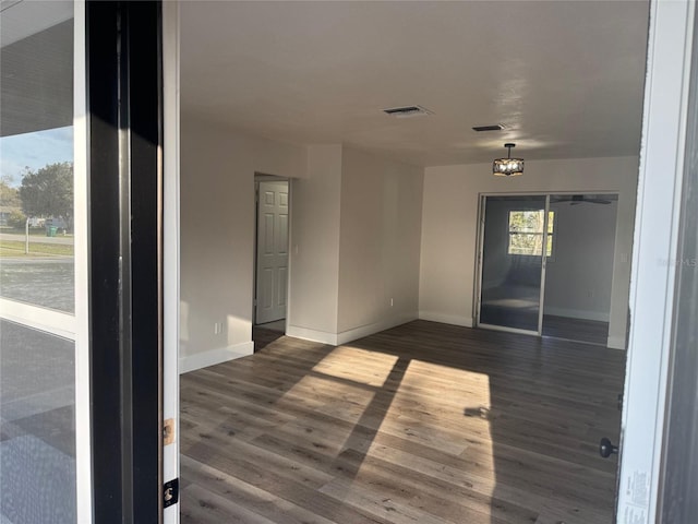 empty room featuring visible vents, baseboards, and dark wood finished floors