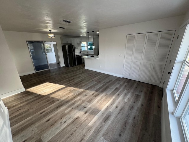 unfurnished living room with baseboards, visible vents, dark wood finished floors, and a sink