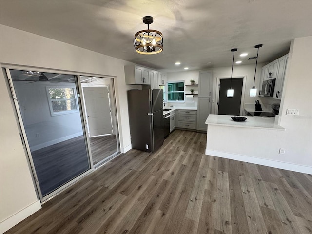 kitchen featuring baseboards, wood finished floors, freestanding refrigerator, a peninsula, and open shelves