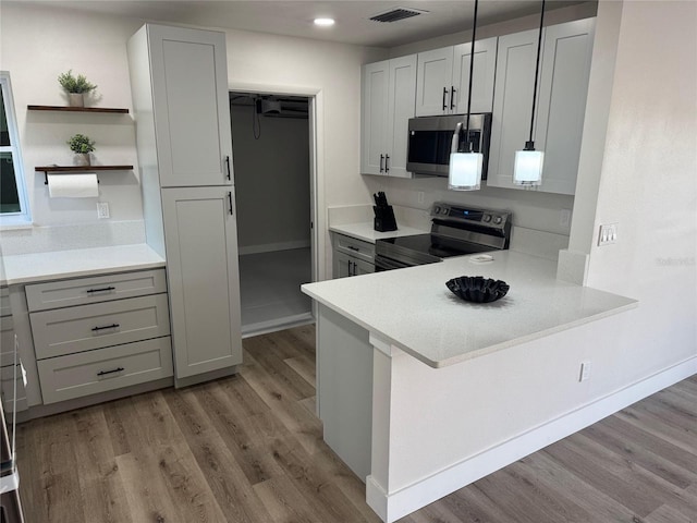 kitchen with stainless steel appliances, light wood-style flooring, light countertops, and visible vents