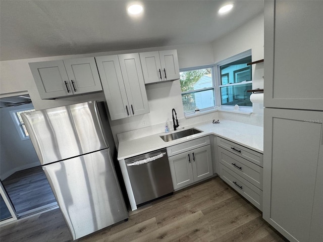 kitchen featuring wood finished floors, light countertops, appliances with stainless steel finishes, and a sink