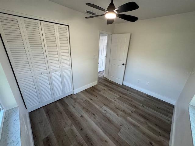 unfurnished bedroom featuring a closet, visible vents, ceiling fan, wood finished floors, and baseboards