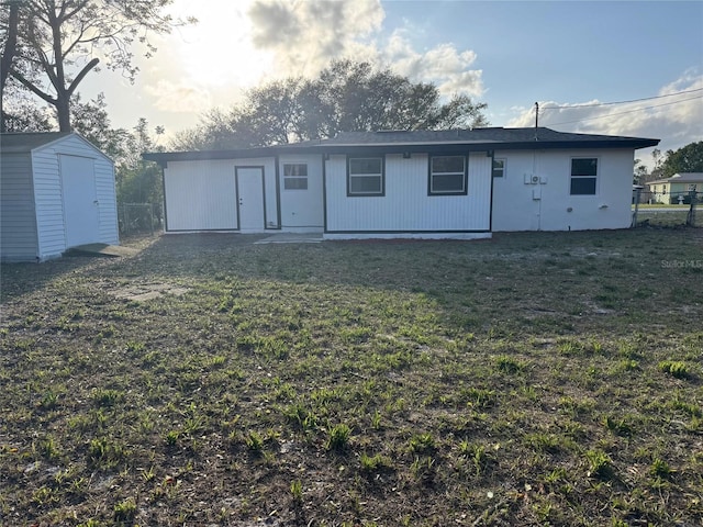 rear view of house with a storage shed, a lawn, an outdoor structure, and fence