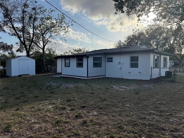 back of house with a yard, a shed, fence, and an outbuilding