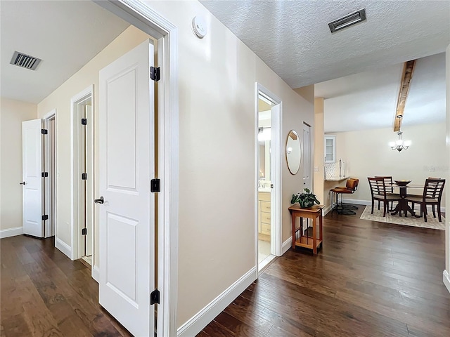 hallway featuring dark wood-type flooring, visible vents, and baseboards