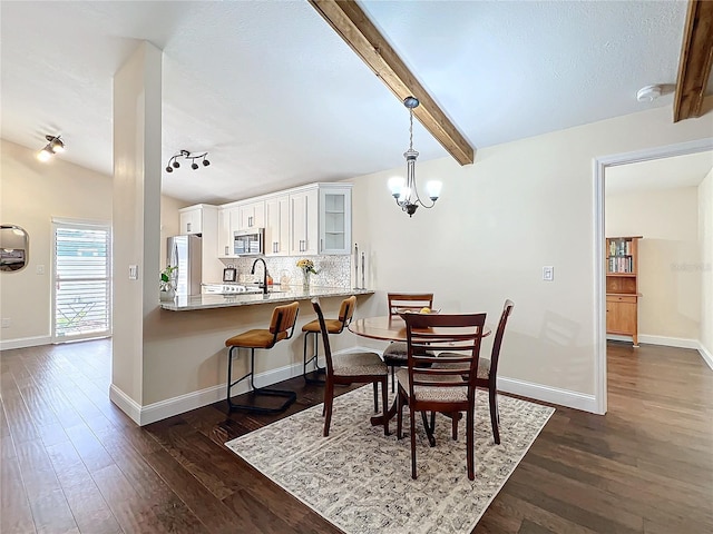 dining area featuring baseboards, dark wood finished floors, lofted ceiling with beams, a notable chandelier, and track lighting