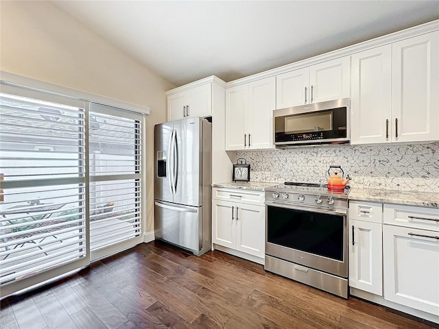 kitchen featuring vaulted ceiling, appliances with stainless steel finishes, backsplash, and white cabinetry