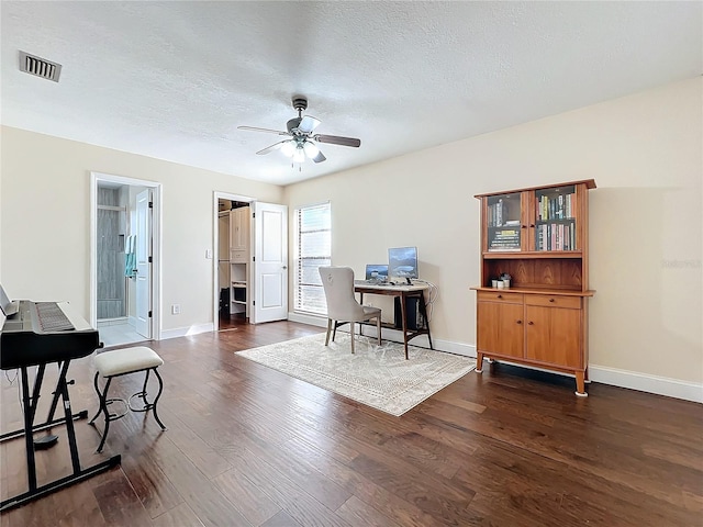 office space featuring dark wood finished floors, visible vents, a ceiling fan, a textured ceiling, and baseboards