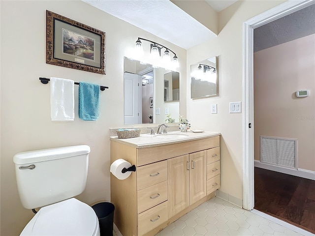 bathroom with tile patterned flooring, toilet, vanity, visible vents, and baseboards