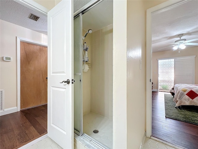 bathroom with visible vents, ensuite bathroom, a ceiling fan, a stall shower, and a textured ceiling