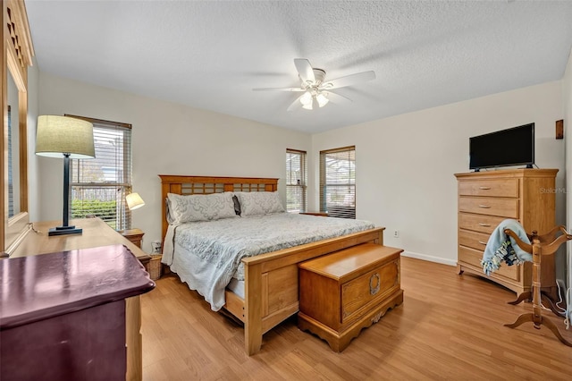 bedroom featuring a textured ceiling, light wood finished floors, and multiple windows