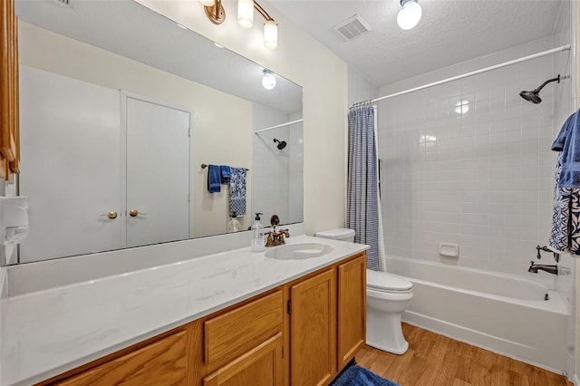 bathroom featuring toilet, wood finished floors, vanity, visible vents, and shower / bath combination with curtain