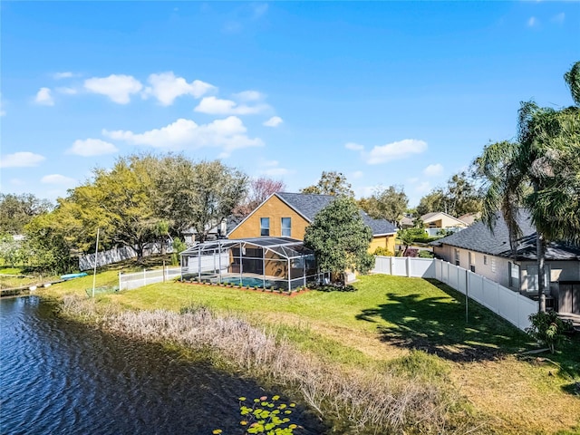 back of property featuring a yard, a water view, glass enclosure, a fenced backyard, and an outdoor pool