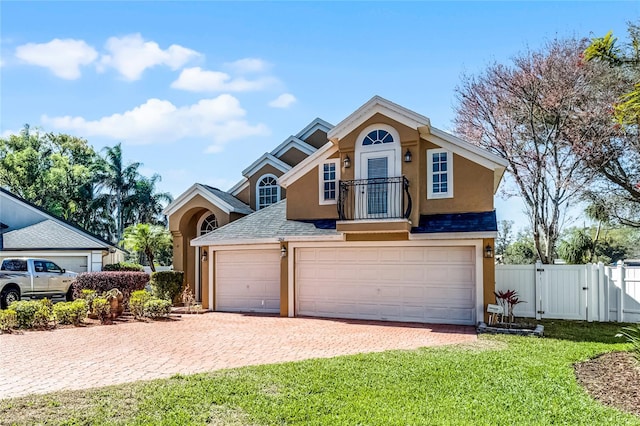 view of front of property featuring decorative driveway, stucco siding, a gate, fence, and a front lawn