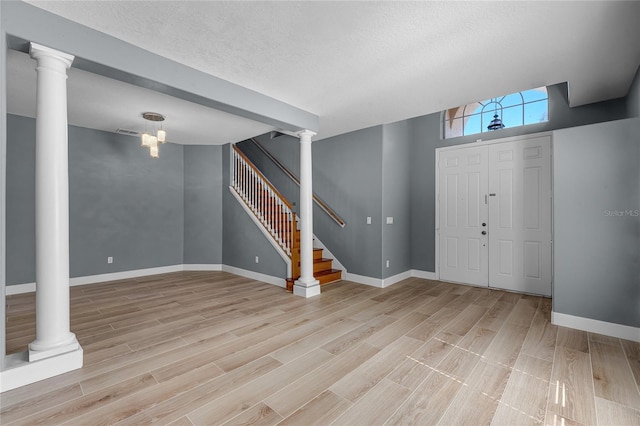 entryway with baseboards, light wood-style floors, stairway, and ornate columns