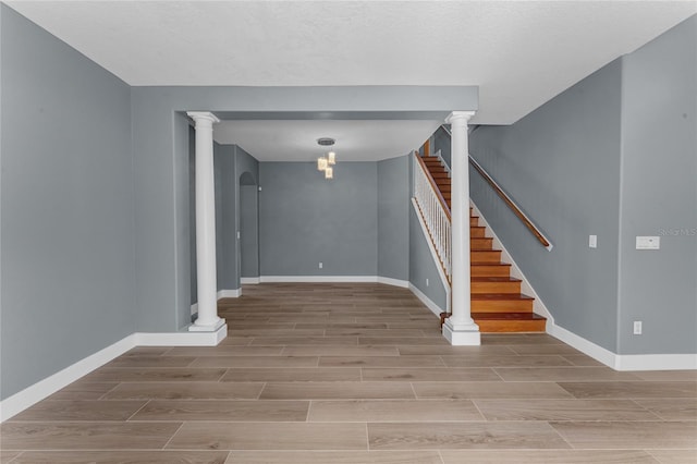 interior space with baseboards, decorative columns, and wood tiled floor