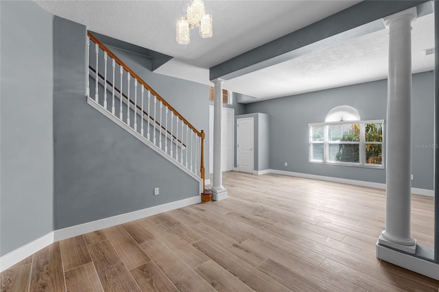 unfurnished living room with decorative columns, stairs, baseboards, and wood finished floors