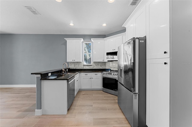 kitchen featuring visible vents, appliances with stainless steel finishes, white cabinets, a sink, and a peninsula