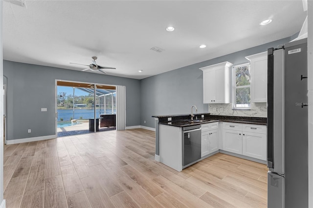 kitchen with a peninsula, light wood finished floors, white cabinets, and stainless steel appliances