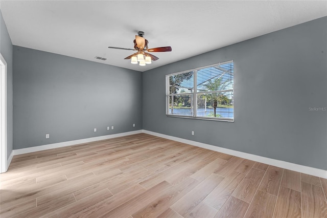 empty room with a ceiling fan, baseboards, visible vents, and light wood finished floors