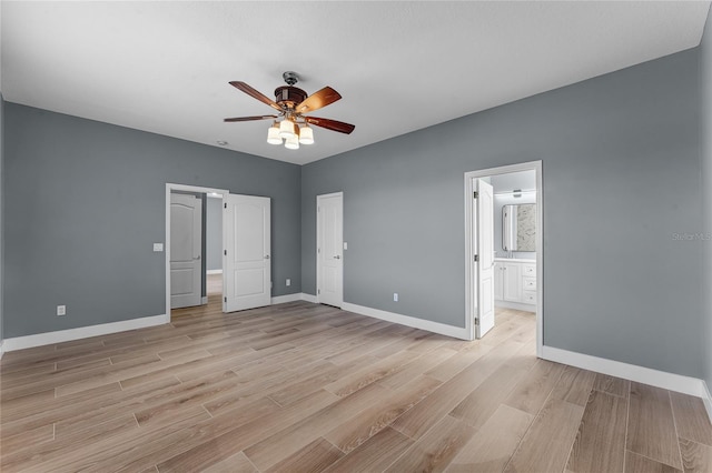 unfurnished bedroom featuring light wood-style floors, ceiling fan, ensuite bath, and baseboards