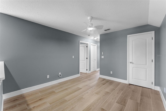 interior space with baseboards, light wood-style flooring, visible vents, and a textured ceiling