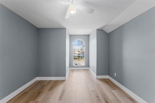 empty room with a ceiling fan, a textured ceiling, baseboards, and wood finished floors