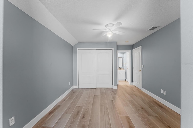 unfurnished bedroom featuring a textured ceiling, ceiling fan, visible vents, baseboards, and light wood-type flooring