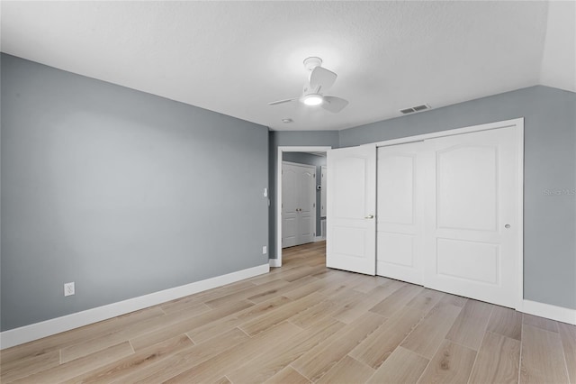 unfurnished bedroom featuring light wood finished floors, a closet, visible vents, a ceiling fan, and baseboards