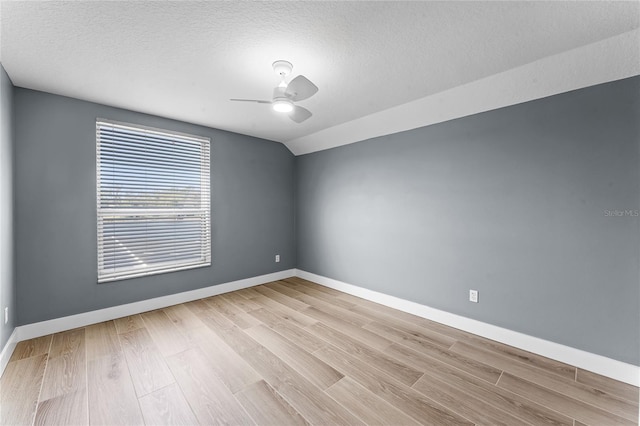 spare room with vaulted ceiling, a textured ceiling, wood finished floors, and baseboards