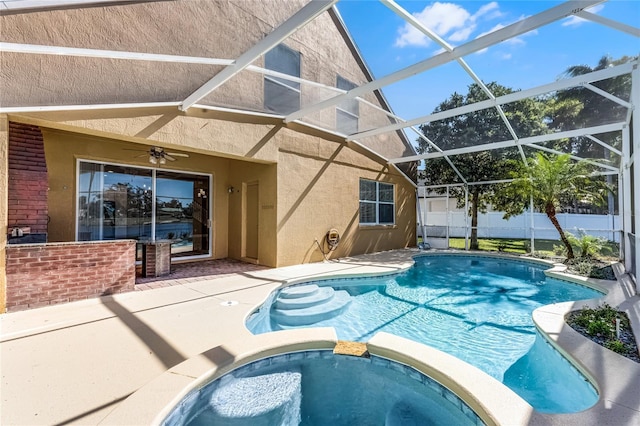 view of swimming pool featuring a ceiling fan, a pool with connected hot tub, a patio area, and a lanai