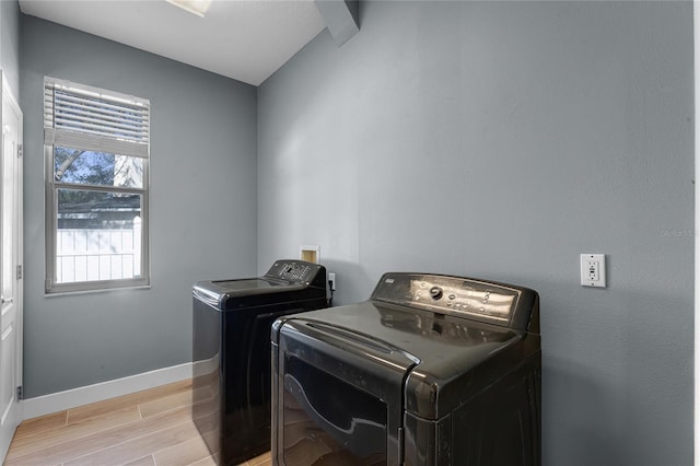 laundry area featuring laundry area, baseboards, light wood finished floors, and separate washer and dryer