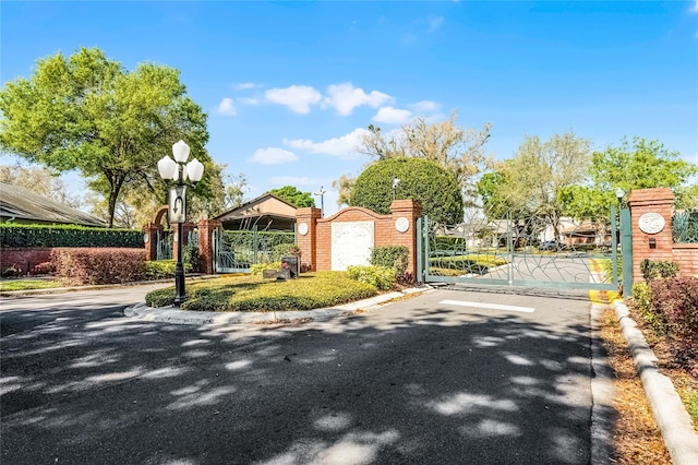 view of road featuring street lights, curbs, a gated entry, and a gate