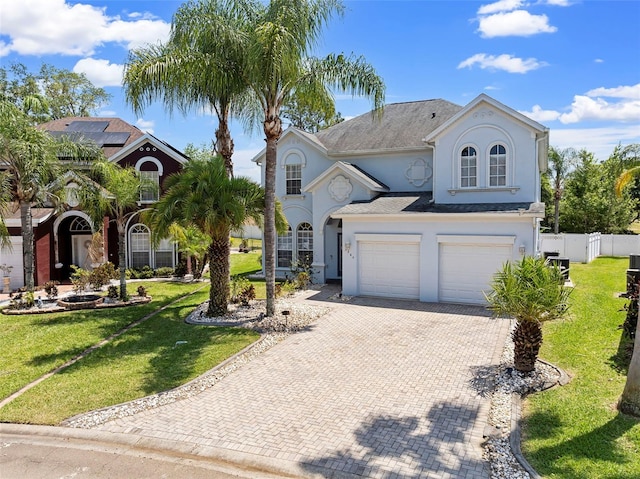 view of front of house with a garage, a front lawn, decorative driveway, and fence