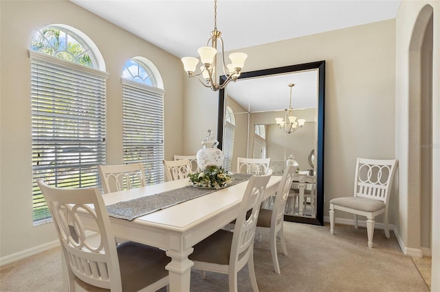 dining area featuring a chandelier, light carpet, and baseboards