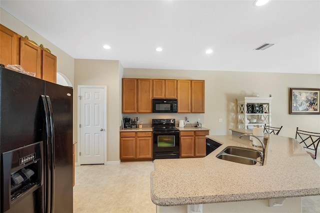 kitchen with visible vents, brown cabinets, black appliances, a sink, and recessed lighting