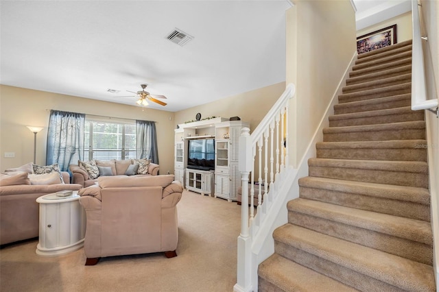 living area with visible vents, ceiling fan, and stairs