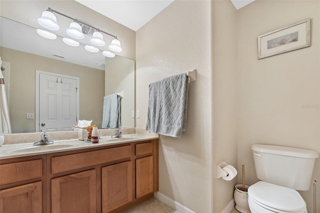 full bath featuring double vanity, a sink, and toilet