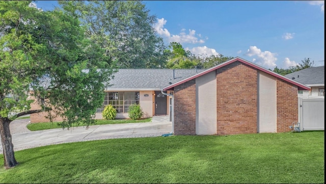 view of front facade with driveway, a front lawn, and brick siding