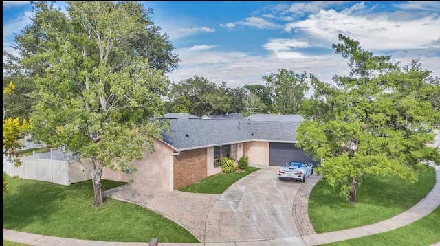 single story home with decorative driveway, stucco siding, a front yard, fence, and a garage