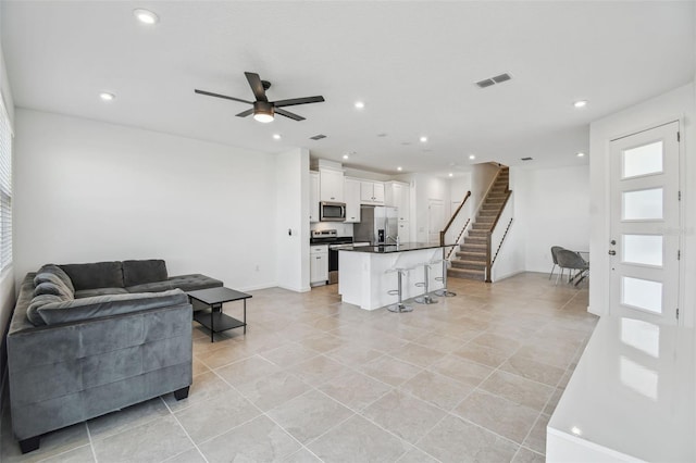 living area featuring a ceiling fan, recessed lighting, visible vents, and stairs