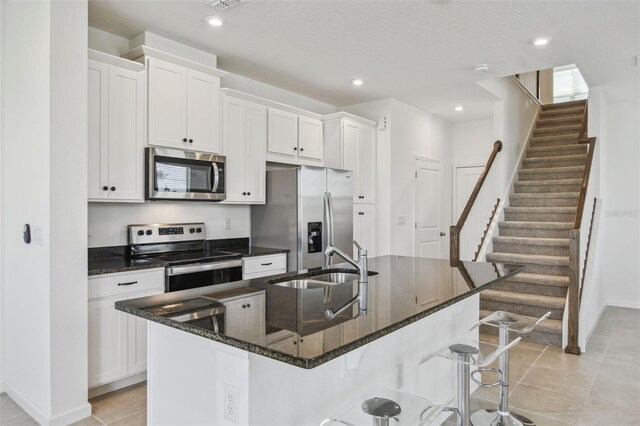 kitchen with a kitchen bar, appliances with stainless steel finishes, white cabinets, and a sink