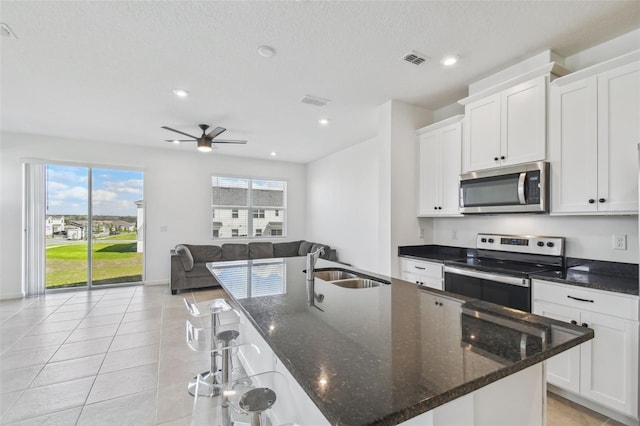 kitchen featuring a center island with sink, stainless steel appliances, visible vents, white cabinetry, and a sink