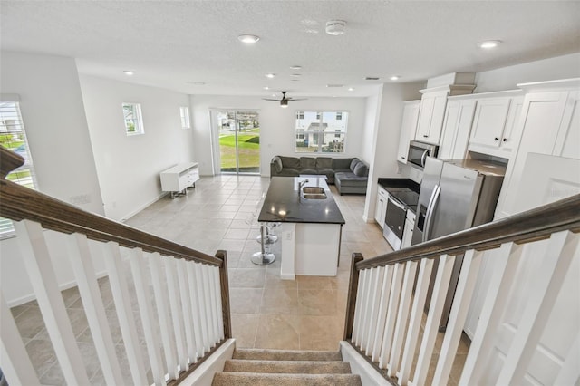 stairs featuring baseboards, a ceiling fan, tile patterned floors, a textured ceiling, and recessed lighting