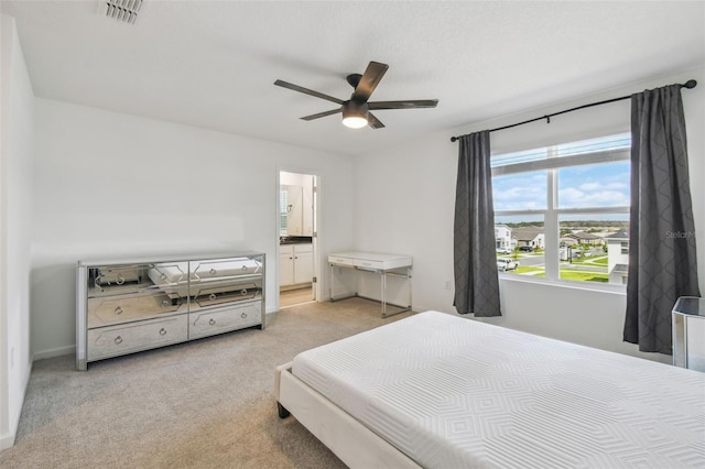 bedroom featuring light carpet, baseboards, visible vents, a ceiling fan, and ensuite bath