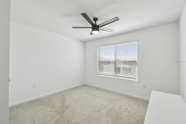 carpeted spare room with ceiling fan, a textured ceiling, and baseboards