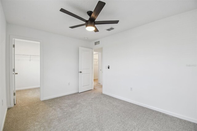 unfurnished bedroom featuring light carpet, visible vents, and a walk in closet