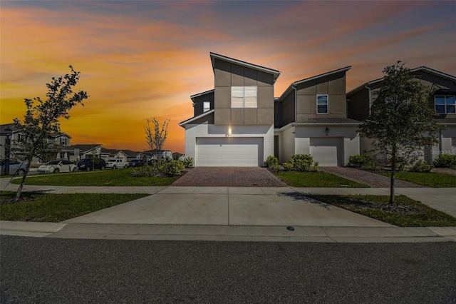 contemporary house with a garage, decorative driveway, and stucco siding