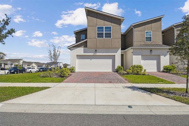 contemporary house featuring a garage, decorative driveway, and stucco siding