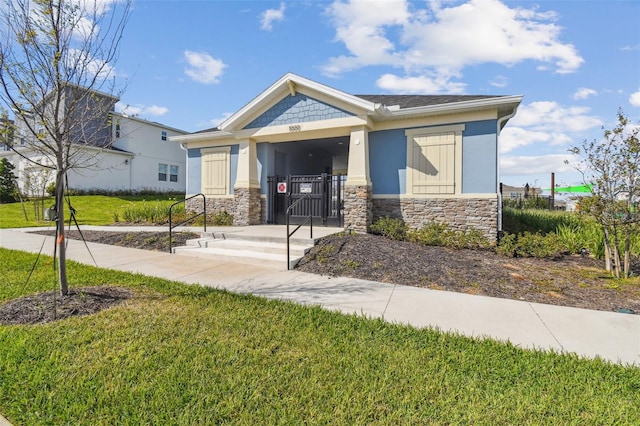 view of front of property with stone siding, a front lawn, a gate, and stucco siding